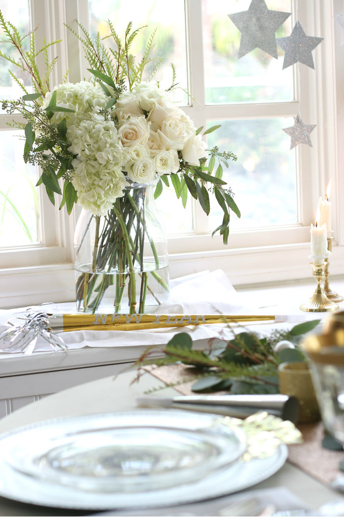 Elegant white roses and hydrangeas, glittery stars and brass candlesticks are simple elements that work perfectly with the tablescape.