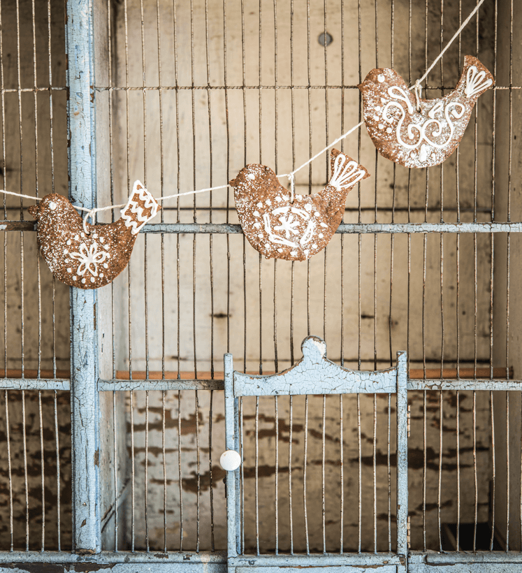 Antique chicken coop with decorative gingerbread birds strung up on the front. 
