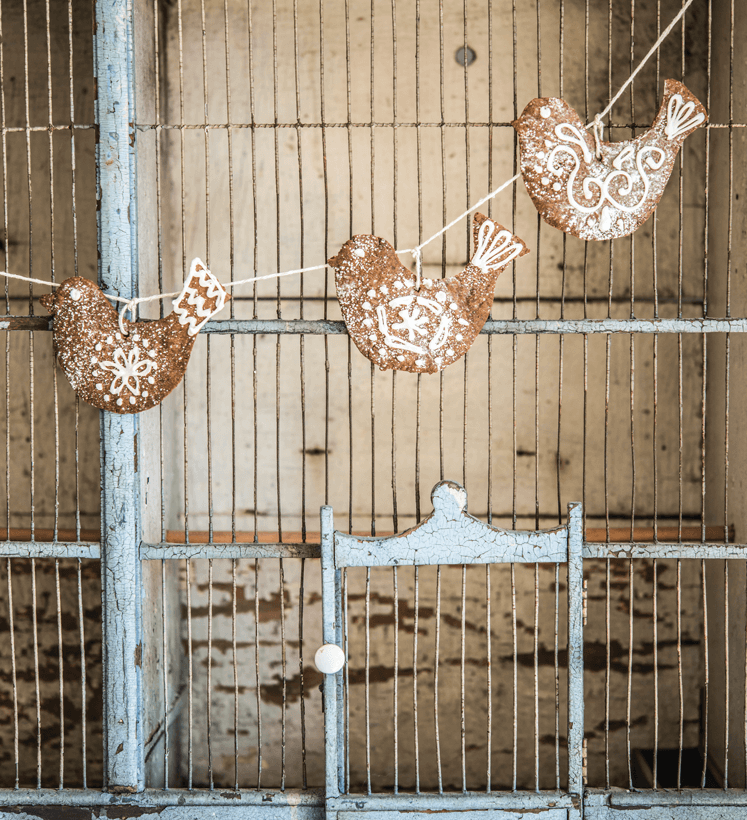 Antique chicken coop with decorative gingerbread birds strung up on the front.