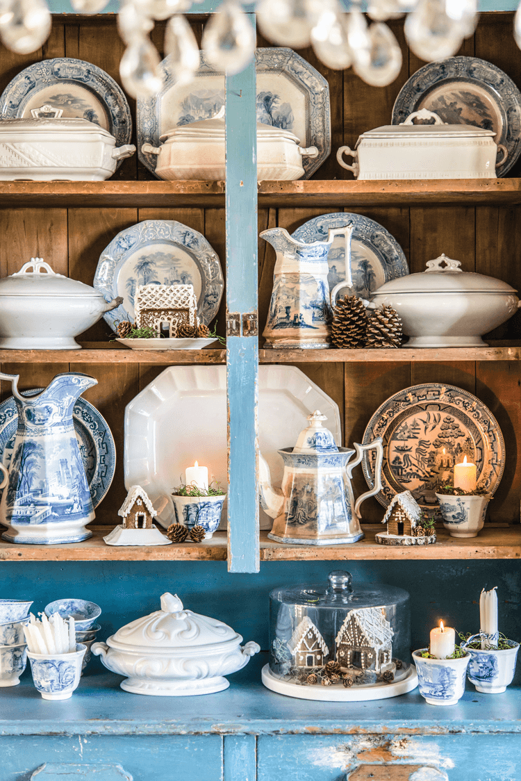 China cabinet with blue and white dishes and small Gingerbread Décor houses placed throughout. 