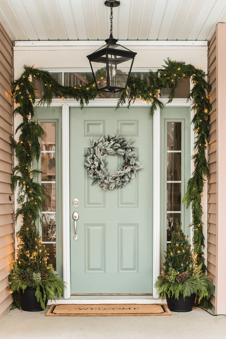 Fresh greenery in the form of natural garland, frosted wreath and topiaries create a welcoming winter scene on Miss Mustard Seed's front door. 