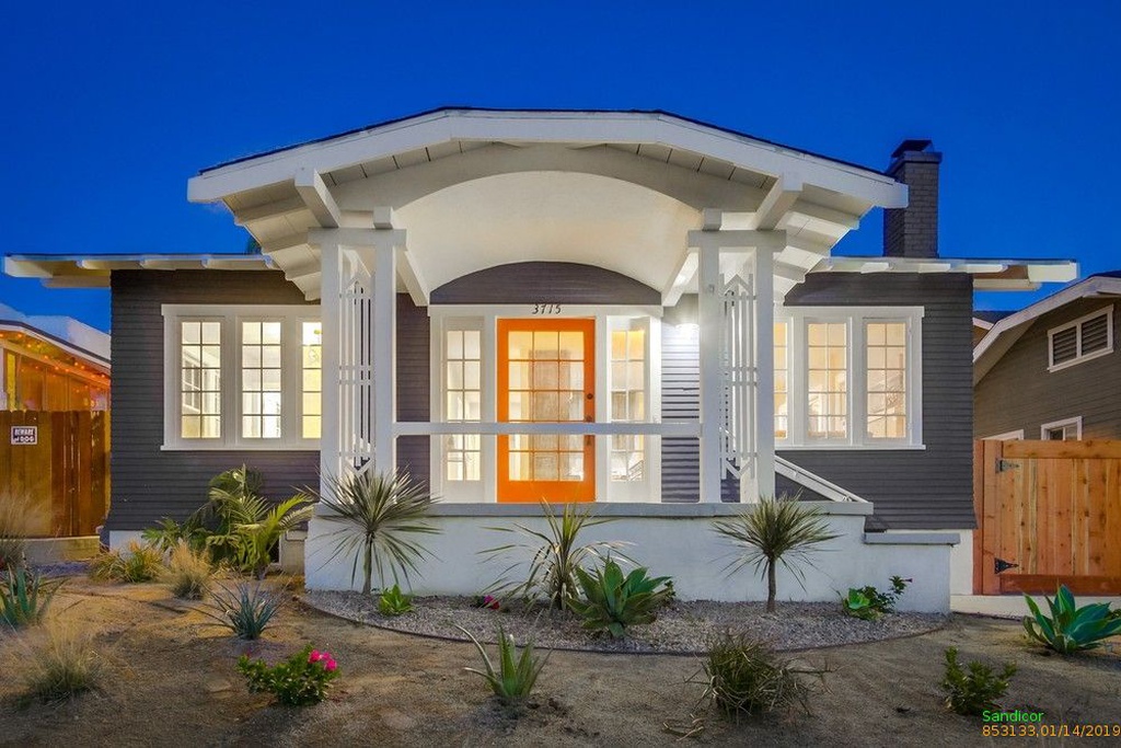 Exterior of a dark gray San Diego cottage with orange door