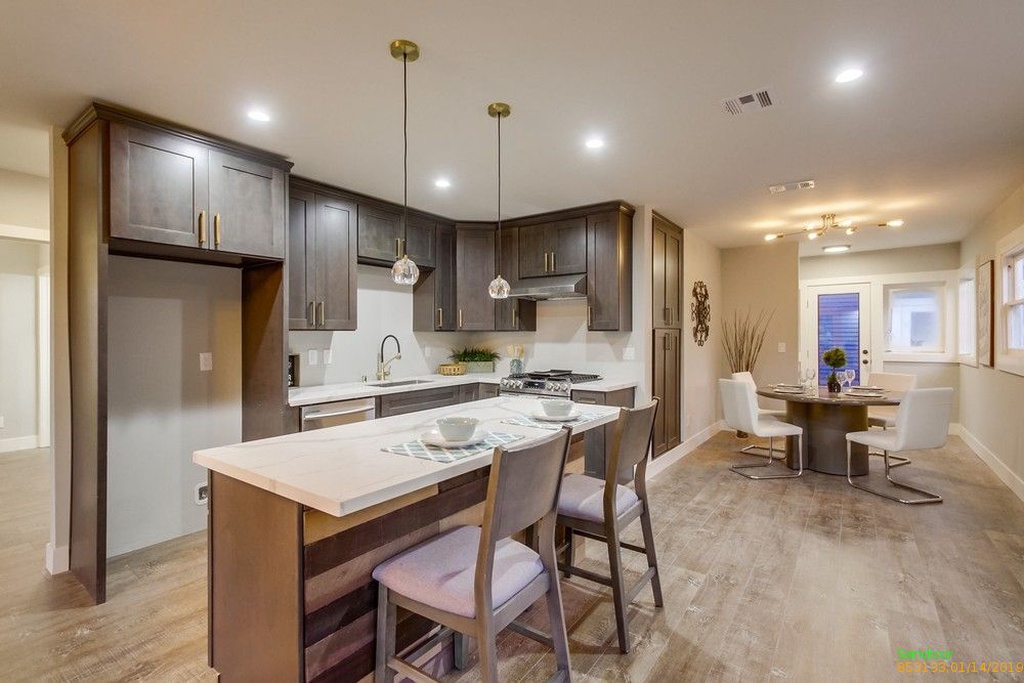 Newly renovated kitchen with brown cabinets, trendy lighting fixtures, and dining area.