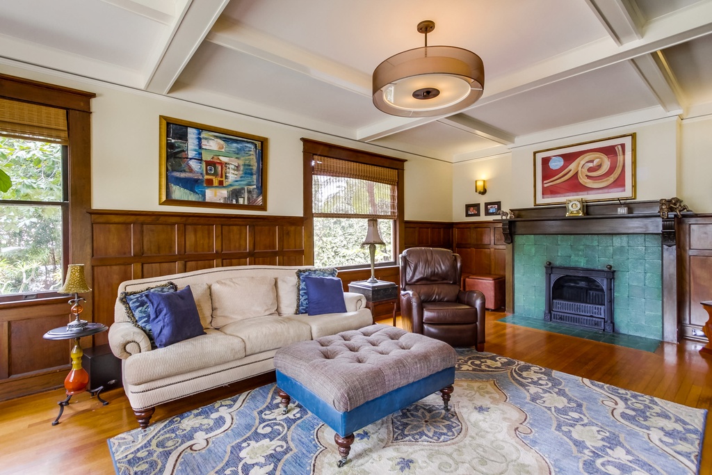 Charming living room of a historic San Diego home with vibrant green fireplace and retro chandelier.