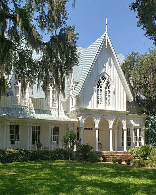 white gothic manor framed by trees