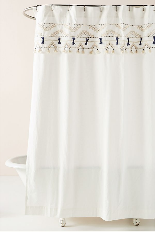 white shower curtain with beige and navy blue embroidery on the top.