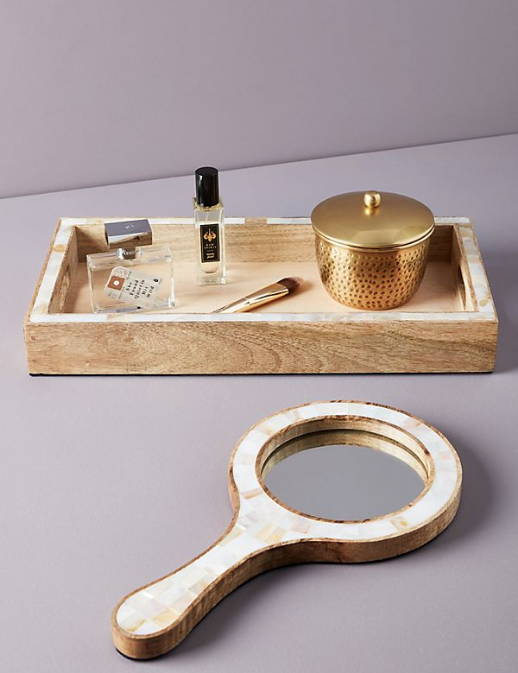 Check out these 10 cottage bathroom accessories! Click here to see more from Cottages and Bungalows. #cottage #bathroom #bathroomaccessories Alt Text: A wooden tray and hand mirror with mother-of-pearl accents.