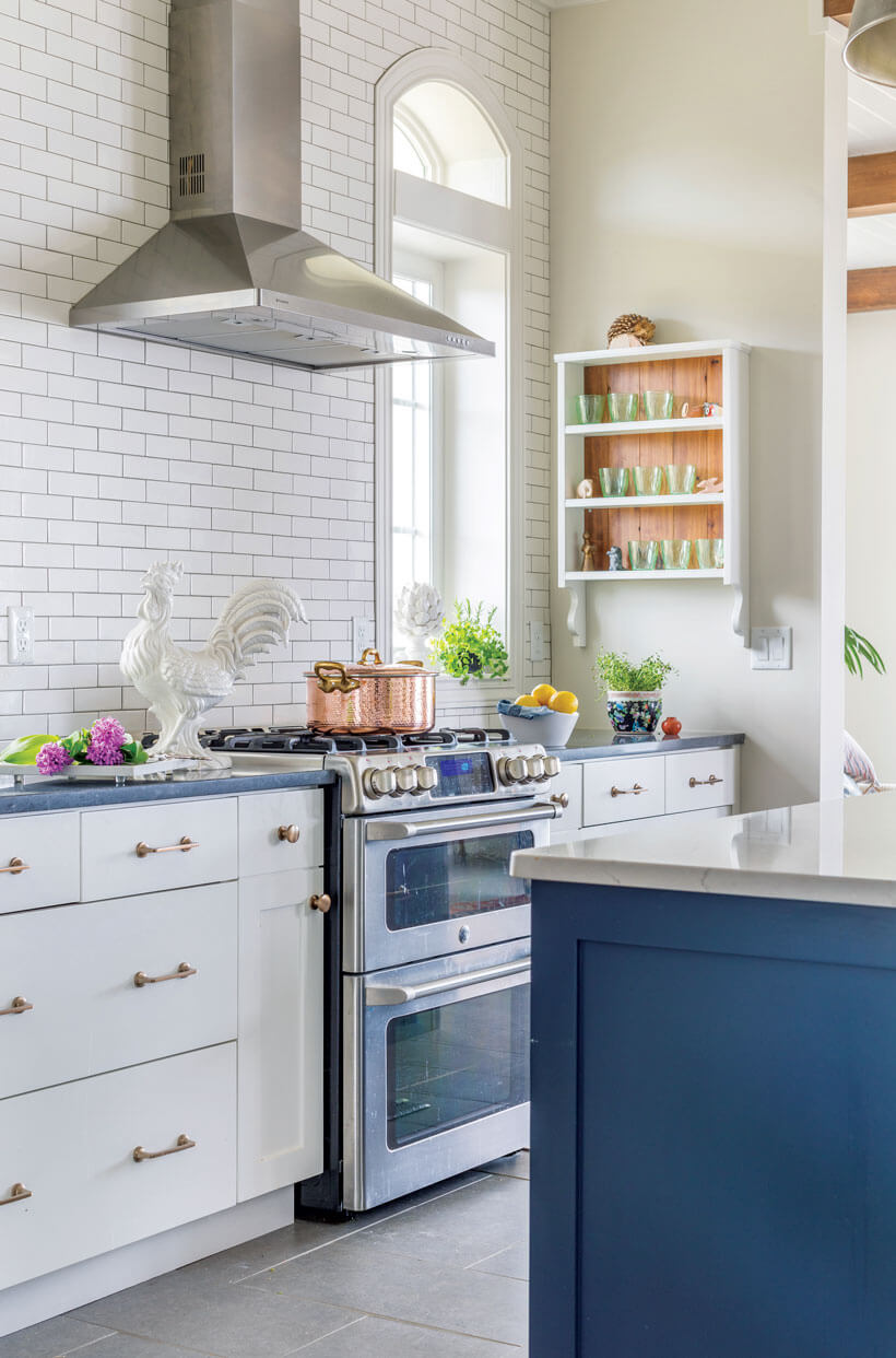 A white kitchen with a blue island and subway-tile backsplash.