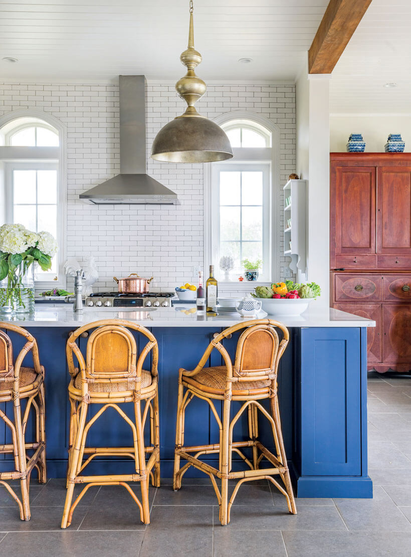 Natural light pours into the kitchen that features a white-tile backsplash and a blue and white granite-covered island.