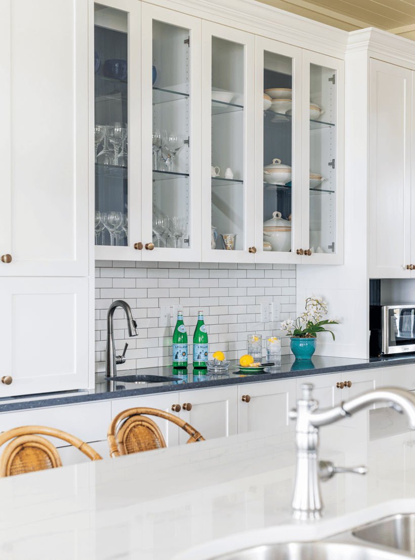 A white kitchen with open shelving that shows off china dishes.