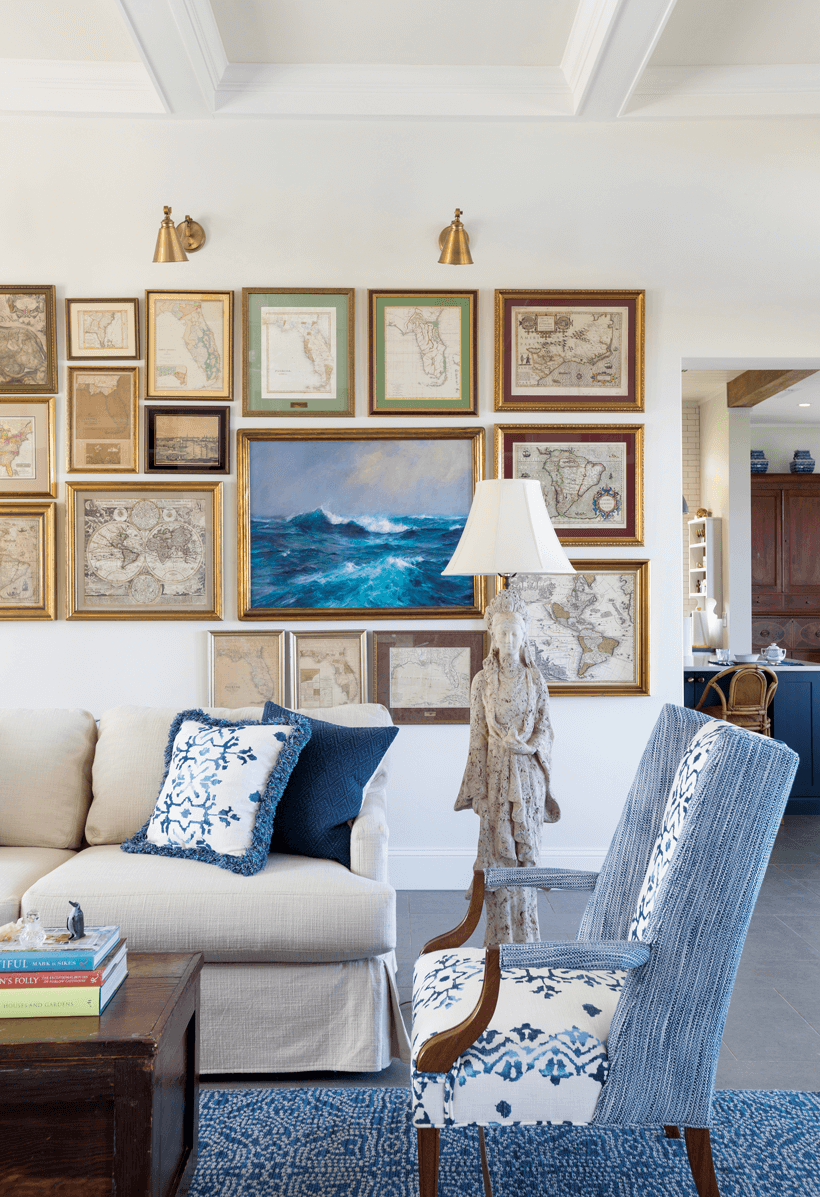 A living room with a gallery wall, blue and white chairs and pillows, and a unique lamp.