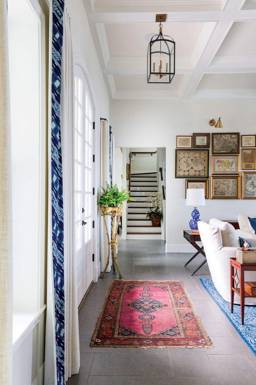 A living room with a red oriental rug and blue curtains.