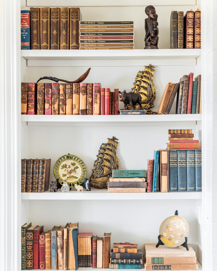 White shelves filled with old books as well as decorative antiques.