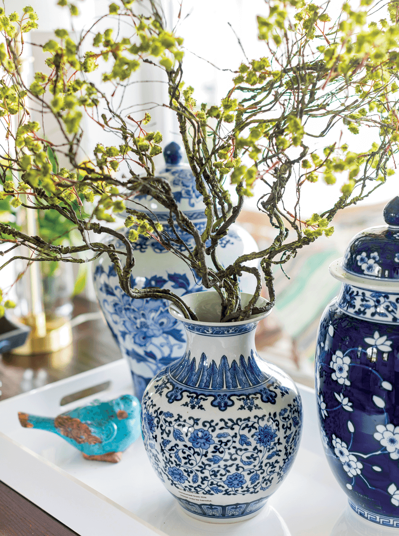 A white and blue vases with decorative tree branches in it.