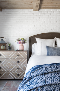 A bedroom with a wall of exposed brick, painted white to match the rest of the room.