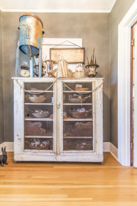 An old display case with glass doors filled with old metal bowls.