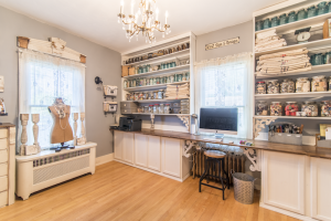 A craft room with open shelves that hold fabric and mason jars filled with crafting supplies.