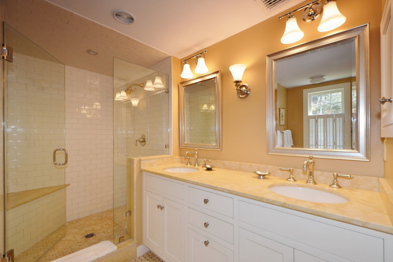 A bathroom with yellow walls and countertops and a glass shower.