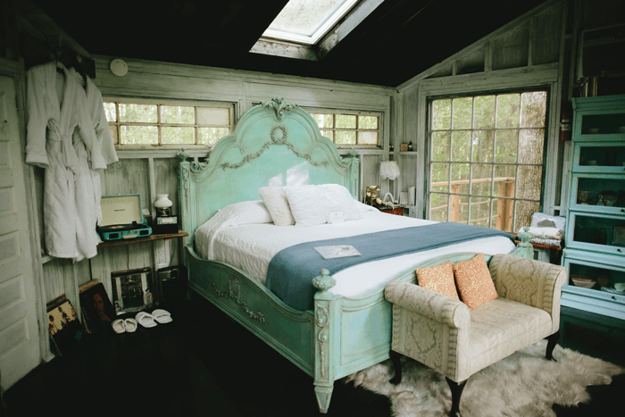 The antique turquoise bed makes the treehouse getaway a romantic place to stay