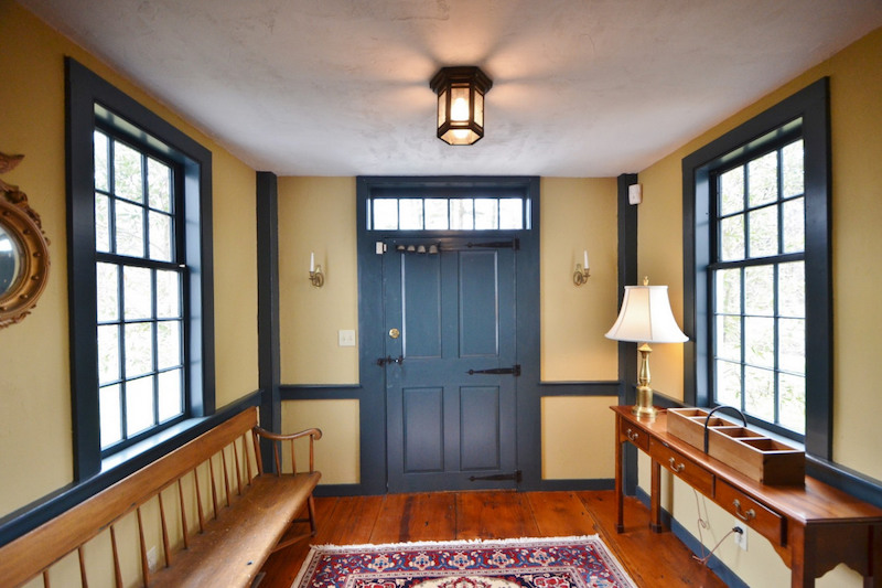 An entryway with light yellow walls and a blue door and window frames. 