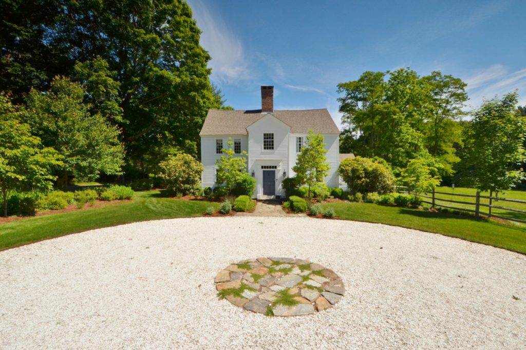 Historic white cottage set back on a circular driveway.