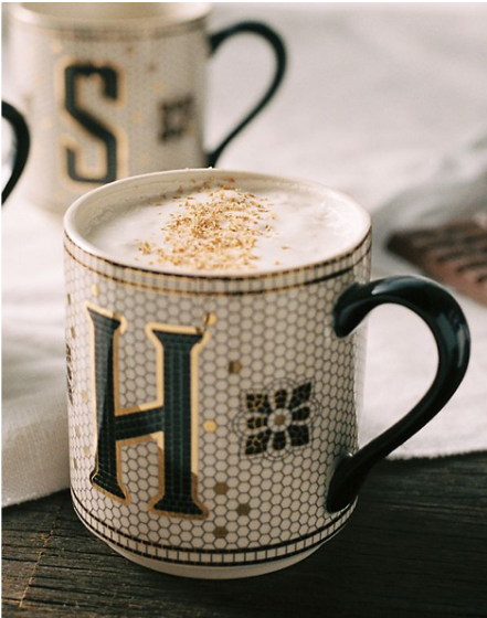 Mug with subway tile design, monogram letter H and a black handle filled with a latte.