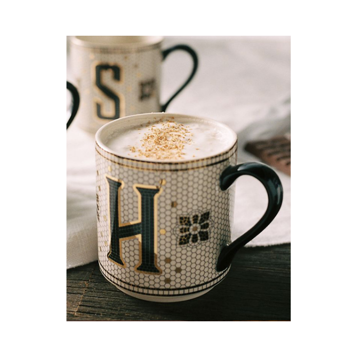 Mug with subway tile design, monogram letter H and a black handle filled with a latte.