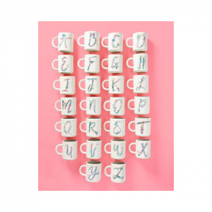 Pink background with alphabet monogramed white mugs laid out.