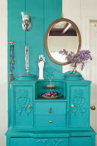 A bright teal vanity with a shiplap wall, partially painted the same bright teal as the vanity.