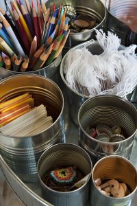 Soup cans being used to hold pencils, paper tags, and other crafting supplies.