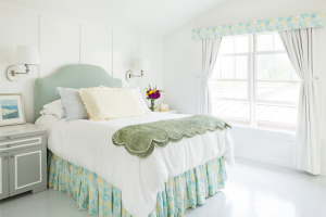 A bedroom with white floors, walls, and ceiling, with green accents in the bed covers and curtains.