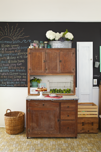 A kitchen with a wall of chalkboard paint that is being used to write tasks down.