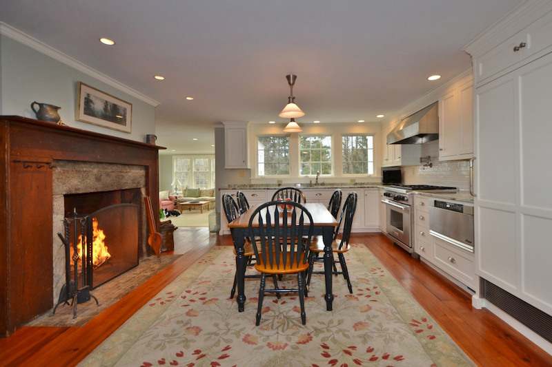 A modern kitchen with a farmhouse table and chairs and an original 17th century fireplace.