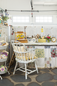A white chair and table with crafting supplies set up in a garage.