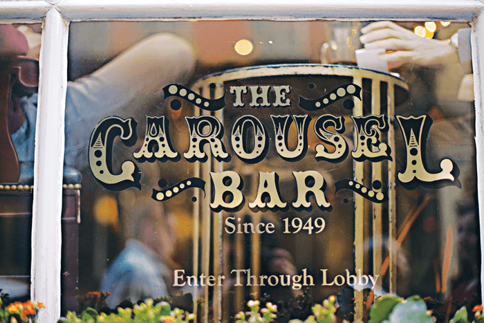 The signage for The Carousel Bar on the front window and a view of the people inside the rotating bar. 