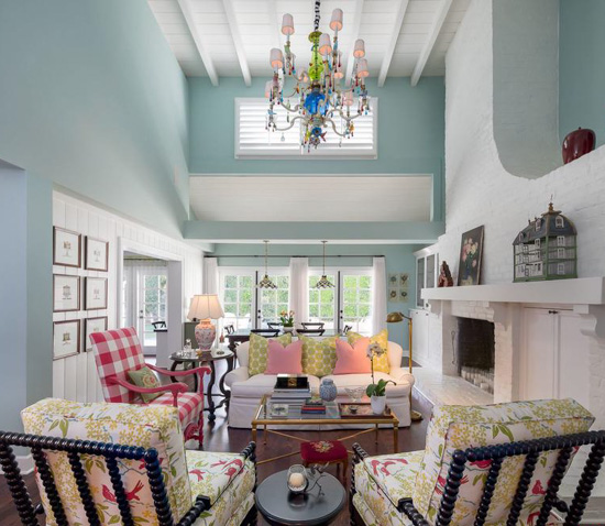 Cozy sitting room filled with chairs and light blue walls and white brick fireplace.