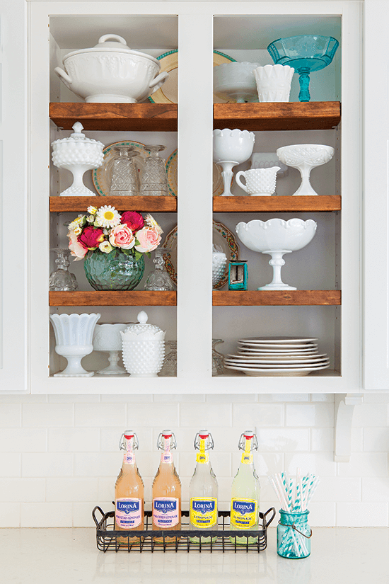 Shaker cabinets with glass panels filled decoratively with fresh flowers and milk glass. 