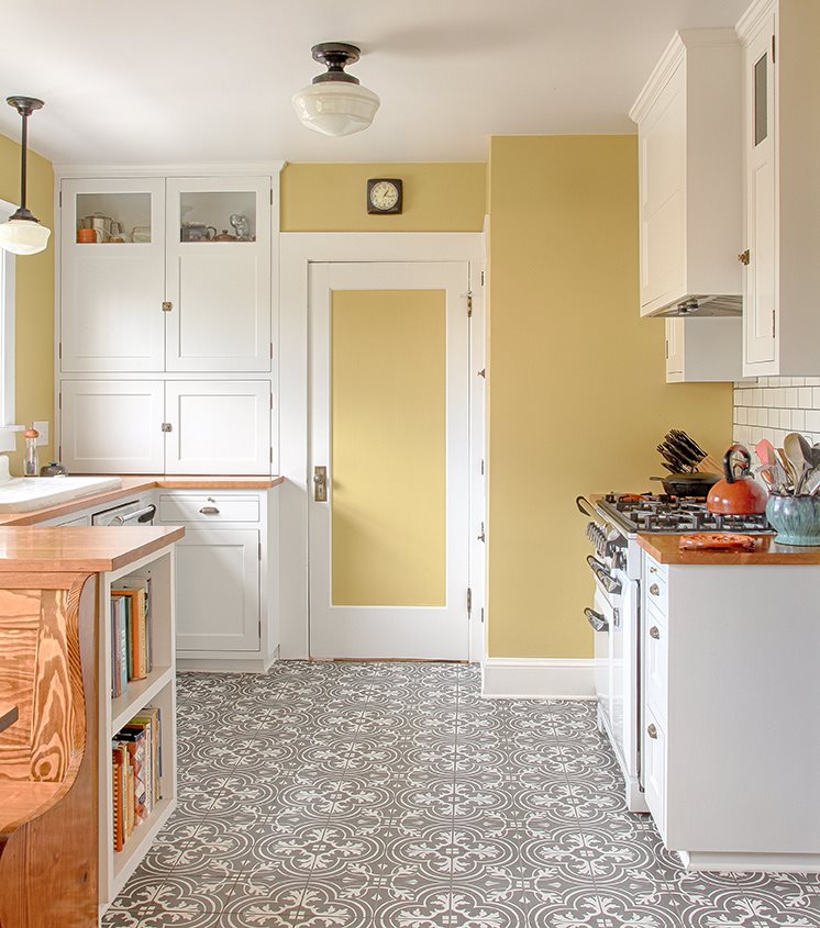 A kitchen with pale yellow walls and a blank-and-white patterned floor.