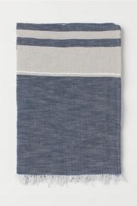 A blue and white throw with fringe on the short sides.