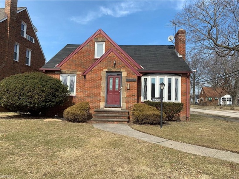 A brick cottage with a dark red front door.