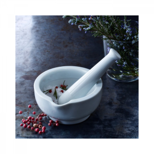 White mortar and pestle with fresh flowers and berries around it as an accent.