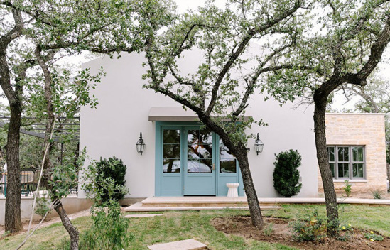 Main building with light blue doors and wall sconces surrounded by trees.