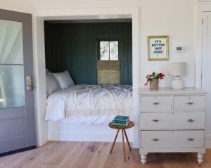 Cottage room with a tucked away bed and a rustic dresser.