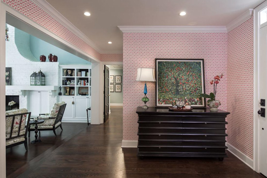 Pink hues cover the walls in this entryway accented with dark wood decor pieces. 