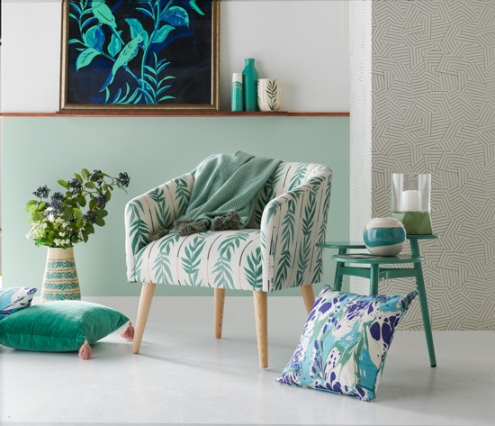 Mint green hues in this seating vignette. Large wall art, ceramic vases, cozy armchair, side table and throw pillows.