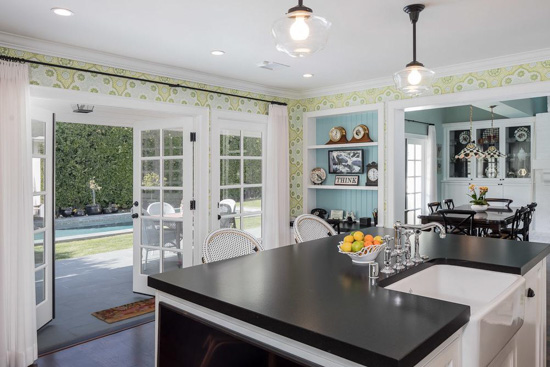 Open concept kitchen with black counter tops and wide open French doors.