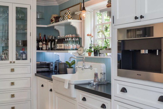 Farmhouse sink surrounded by inlayed appliances and custom white cabinetry.