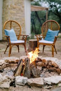 Stone ring with a blazing bonfire and two cozy chairs with blue cushions.