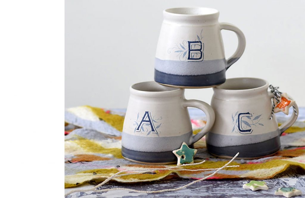Stack of handmade ceramic monogrammed mugs with letters A, B , and C