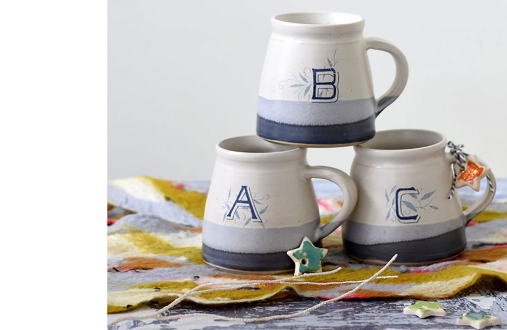 Stack of handmade ceramic monogrammed mugs with letters A, B , and C 